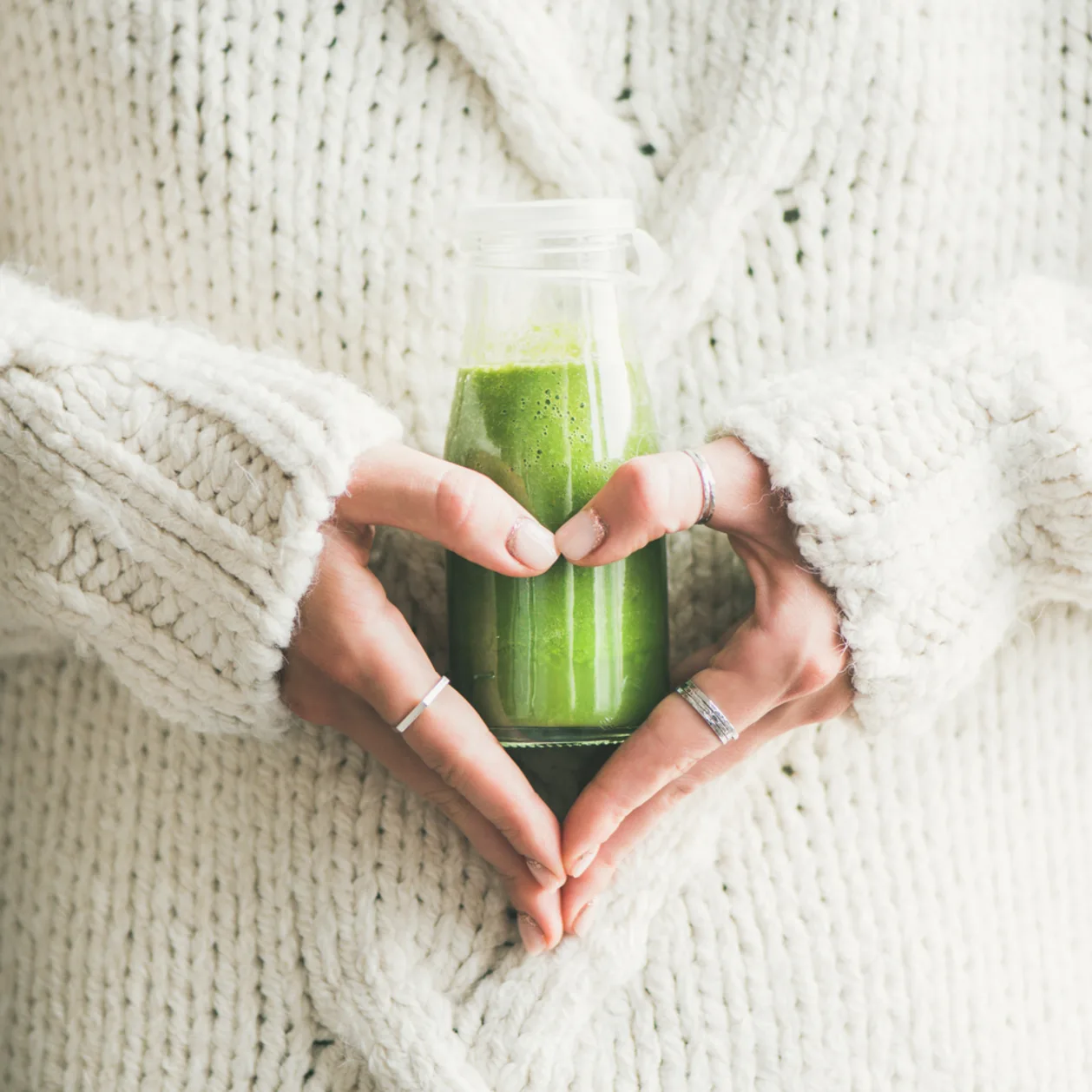 green detox smoothie drink in woman's hands